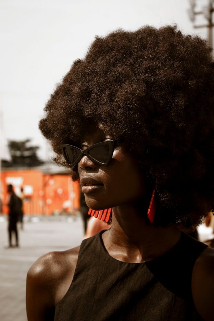 Stylish portrait of a woman with an afro hairstyle and sunglasses in Lagos, Nigeria.